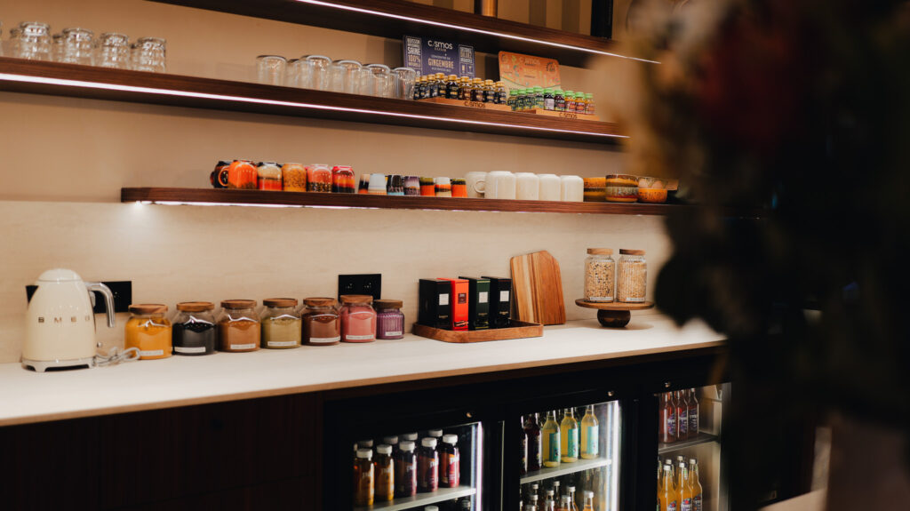 étagères avec bocaux de condiments, verres et bouteilles, plaque chauffante SMEG sur un comptoir clair devant un