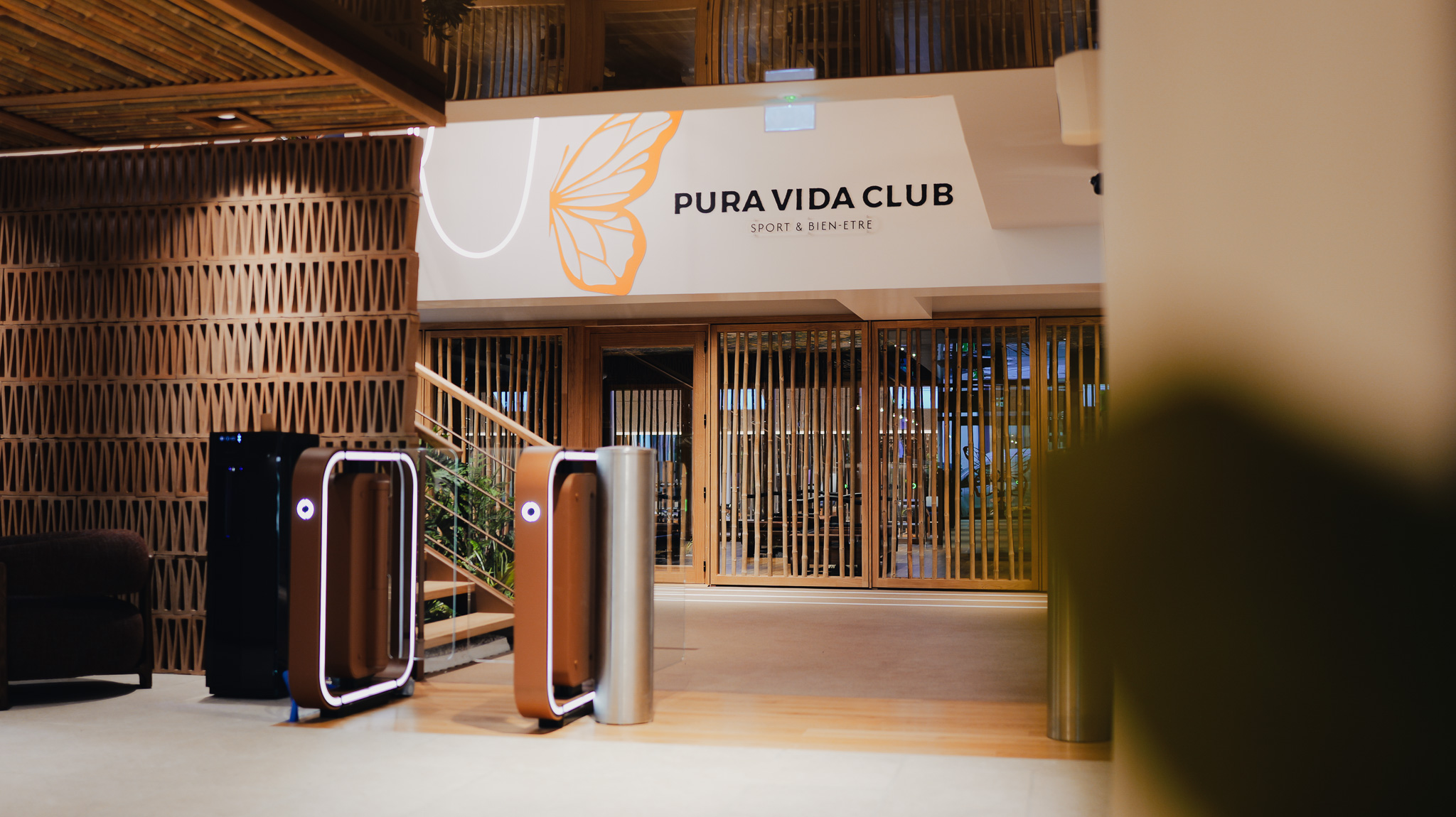 Entrée moderne avec tourniquets et panneau mural PURA VIDA CLUB sport et bien-être